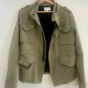 Army jacket/ utilityjacka från Neo Noir - Säljer en jättefin army/utilityjacka från Neo Noir. Fina detaljer och har fyra fickor med tryck-knappar, samt stängning av jackan med tryckknappar samt en dragkedja. Mjukt skönt och stretchigt material. Lätt fodrad i ett svart mjukt tyg. Liten i storleken, är mer som en M.