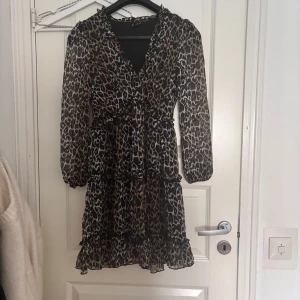 Leopardmönstrad volangklänning - Säljer en snygg leopardmönstrad klänning med volangdetaljer och v-ringning. Klänningen har långa ärmar och markerad midja. Materialet är lätt och luftigt🐆