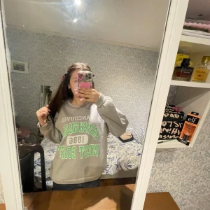 Grå sweatshirt med tryck från SHEIN - Säljer en grå sweatshirt från SHEIN med texten 'Vancouver British Columbia 1886 West Coast' i vitt och grönt. Tröjan har rund hals och långa ärmar. Perfekt för en avslappnad stil.