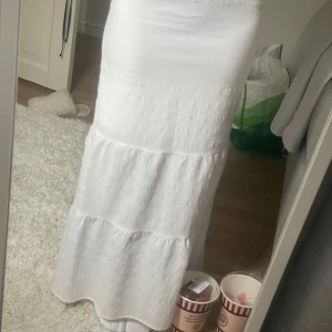 Vit långkjol med volang - Säljer en vit långkjol med volangdetaljer. Kjolen har en luftig och flowy känsla, perfekt för varmare dagar. Enkel och stilren design som passar till många olika outfits. Passar XXS/XS🩷