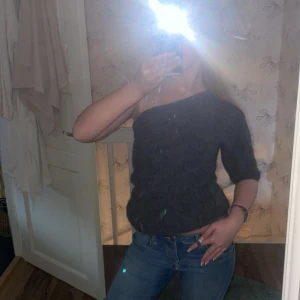 Mörkgrå offshoulder stickad tröja - Säljer en mörkgrå stickad tröja med offshoulder-design. Tröjan har en lös passform och är tillverkad i ett mjukt, fluffigt material. Perfekt för dig som vill ha en trendig och bekväm look.