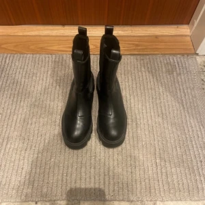 Svarta boots - Snygga svarta boots i skinn med rund tå och dragkedja på sidan. Perfekta för en stilren look.