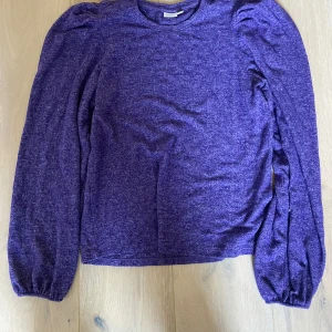Lila långärmad tröja - Säljer en snygg lila tröja med långa ärmar och puffiga axlar. Perfekt för att ge din outfit en färgklick. Tröjan har en mjuk och bekväm känsla.