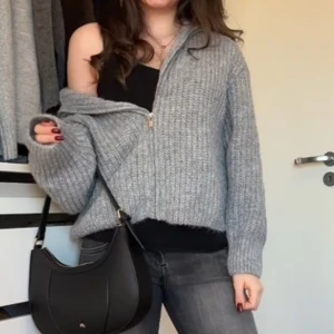 Grå stickad kofta med dragkedja från H&M Divided - Mysig grå stickad kofta från H&M Divided med dragkedja framtill och hög krage. Koftan har en ribbad struktur. Perfekt för lager-på-lager och enkel att matcha med jeans! Den är super varm och mysig! Använd endast en gång!