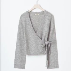 Grå omlottkofta med knyt - Supermjuk grå omlottkofta med knyt i sidan och v-ringning. Använd några få gånger men i väldigt bra skick.