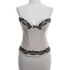 Vit korsett topp - Supersnygg vit korsett med svarta spetsdetaljer och rosett framtill, axelbanden är smala och justerbara💗