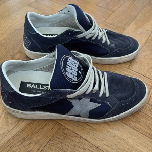 Mörkblå sneakers från Golden Goose Ball Star - Säljer ett par mörkblå Golden Goose Ball Star sneakers med vit stjärndetalj på sidan och vita skosnören. Skorna har rund tå och perforerade detaljer framtill. Märkeslogga på plös och häl. Kommer med originalkartong och dustbag.