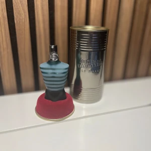 Jean Paul Gaultier Le Male Eau de Toilette - Klassisk herrparfym i en ikonisk blågrön flaska formad som en manlig torso med ljusblå och vita ränder. Kommer med original metallburk. Doften är fräsch och maskulin, perfekt för dig som gillar unika och stilrena flaskor. Den är i en 40 ml flaska med ca 35 ml kvar så den räcker nog ett bra tag 👍 