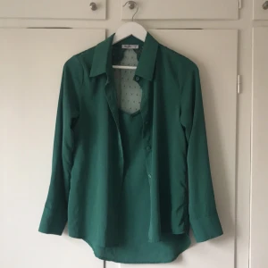 Grön blus med spetsdetaljer - Snygg grön blus från unika paris med långa ärmar och spetsdetaljer på ryggen. Blusen har en klassisk krage och knappar framtill. Strl S