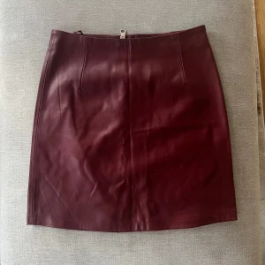 Vinröd läderkjol - Snygg vinröd kortkjol från Bik Bok. Kjolen har en dragkedja baktill. Perfekt både till fest med en söt topp eller tjocktröja och boots på hösten.