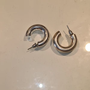 Chunky silverfärgade örhängen - Säljer ett par chunky örhängen i silverfärg med rundad, tjock form. Perfekta för att ge en cool touch till din outfit. Stiftmodell som är enkla att ta på och av🩷