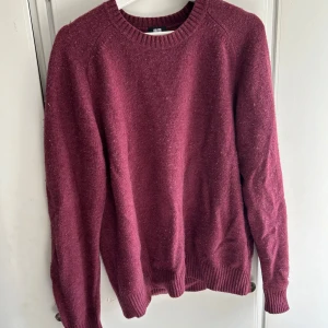 Vinröd stickad tröja från Uniqlo - Säljer en stilren vinröd stickad tröja från Uniqlo. Tröjan har en klassisk rund hals och långa ärmar med ribbade muddar. Perfekt för kyliga dagar och enkel att matcha med olika outfits.