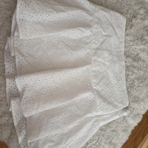 Vit kjol från H&M - Säljer en söt vit kjol från H&M med broderade detaljer. Kjolen har en normal passform och är perfekt för sommarens varma dagar. 🤍☀️den har dragkedja i ena sidan! 