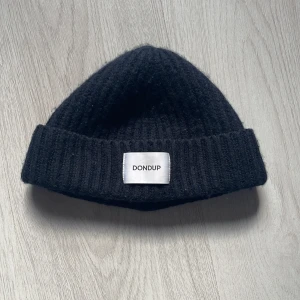 Svart ribbad mössa från Dondup - Snygg svart ribbad mössa från Dondup, tillverkad i Italien. Perfekt för att hålla värmen med stil under kyliga dagar. Märkesetikett framtill ger en exklusiv touch.