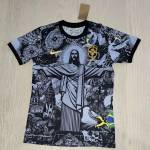 Brasilien fotbollströja - Unik Brasilien fotbollströja med svartvitt konstnärligt tryck av Kristusstatyn i Rio, brasilianska flaggan och detaljer i gult och blått. Kortärmad modell med svarta muddar och rund hals. Perfekt för dig som vill sticka ut.