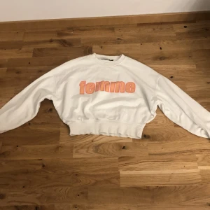 Vit sweatshirt med tryck från Bik Bok - Säljer en vit sweatshirt från Bik Bok i storlek XS. Tröjan har ett rosa tryck med texten 'femme' på bröstet och är långärmad med bred mudd i midjan och vid ärmsluten. Perfekt för en avslappnad och trendig stil.