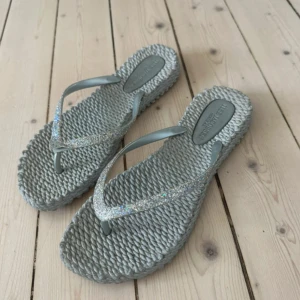 Flip flops   - Säljer ett par grå flip flops med glittriga remmar. Se bild där det gått upp, går att limma 