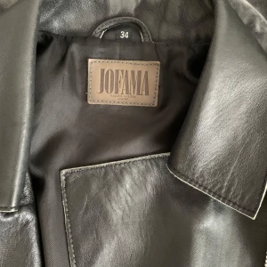 Svart skinnjacka från Jofama - Snygg svart skinnjacka från Jofama med asymmetrisk dragkedja och stilrena detaljer. Jackan har långa ärmar och en klassisk krage. Använd ett fåtal gånger. Väldigt fint skick.