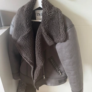 Grå jacka från Zara - Snygg grå/beige-brun jacka från Zara med mjuk fuskpäls på insidan. Aningen varmare färg i verkligheten. Jätteskön och varm jacka!🙏1200kr nypris och använd få gånger❣️🌟Passar XS-M