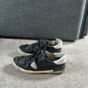 Svarta sneakers från Philippe Model - Säljer ett par svarta sneakers från Philippe Model med vita detaljer på hälen och sidorna. Storlek 44/45. Slitna sulor men annars helt fungerande skick.