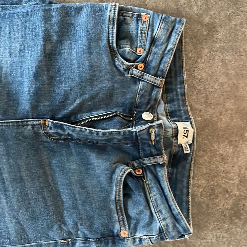 Säljer ett par klassiska blå bootcut jeans från lager157 med fem fickor och dragkedja. Jeansen har en snygg utsvängd passform och normal midja. Perfekta för dig som gillar retrostil och vill ha ett par bekväma jeans till vardags.. Farkut & Housut.