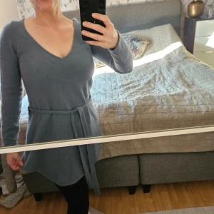 stickad tröja Tiger of sweden jeans  - Mysig lblå stickad klänning med v-ringning och knytskärp i midjan. Långärmad och i mjukt material, perfekt för kyligare dagar. Enkel och stilren design som passar till många tillfällen.