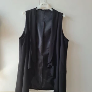 Elegant väst från KappAhl - Elegant svart väst från KappAhl i storlek 46. Västen har en stilren design utan ärmar och är perfekt för att lägga till en extra touch till din outfit. Kan hämtas i Vallentuna.