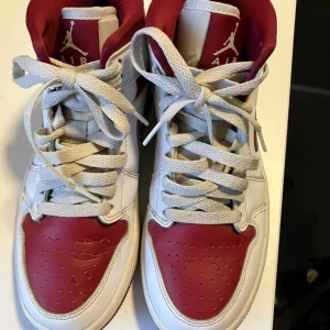 Nike Air Jordans i rött och vitt - Säljer ett par klassiska Nike Air Jordans i rött och vitt. Skorna har snörning och en rund tå, med den ikoniska Air Jordan-loggan på sidan. Perfekta för dig som älskar sneakers med stil och komfort.Nike air Jordan 1, high. Begagnade men i nyskick, lite creases.  Storlek 36.5  