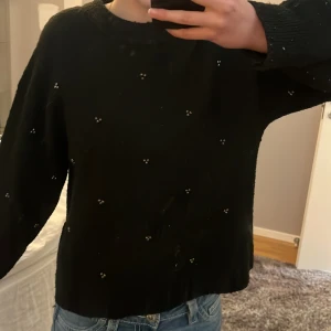 Snygg stickad tröja från H&M - Svart stickad tröja från H&M med små pärldetaljer utspridda över hela tröjan. 🖤✨ Tröjan har rund halsringning, långa ärmar och ribbade muddar vid ärmslut och nederkant. Perfekt för en stilren och enkel look. 