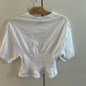 Vit croppad topp från Gina Tricot - Säljer en vit croppad topp från Gina Tricot med korta ärmar och rund halsringning. Toppen har insydda sömmar i midjan som ger en snygg passform och markerad midja. Perfekt till jeans eller kjol!🧚🏻