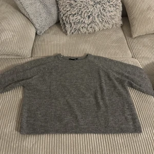 Grå stickad tröja - Säljer en mysig grå stickad tröja med en enkel design. Tröjan har långa ärmar och en rund halsringning. Perfekt för kyliga dagar.