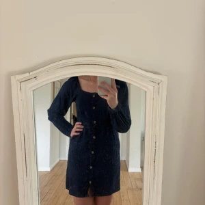 klänning - Snygg mörkblå klänning med knappar framtill och långa ärmar. Perfekt för en stilren look. Klänningen har en smickrande passform och är enkel att styla. Klänningen är i linne