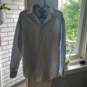 Randig skjorta från Ralph Lauren - Klassisk skjorta från Ralph Lauren i vitt och blått med smala ränder. Skjortans skick är mycket bra. Storleken är S men kan även passa xs 