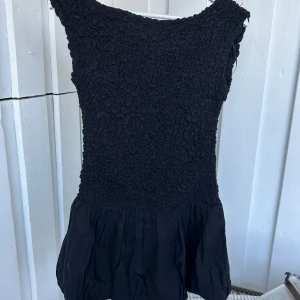 Svart ballongklänning Y balloon tube - Svart kortklänning med ballongformad kjol och tubtopp. Överdelen har ett coolt, krusat tyg som ger en unik textur och kjolen är lätt och luftig. Perfekt för dig som gillar stilrena och trendiga plagg med lite edge.