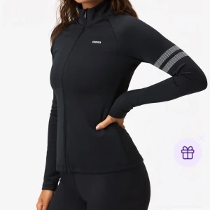 Svart träningsjacka från STRONGER - Nypris 800! Slimmad svart träningsjacka från STRONGER med hel dragkedja, högt krage och reflekterande ränder på ena ärmen. Tillverkad i stretchigt syntetmaterial som andas. Perfekt för löprundan eller gymmet.