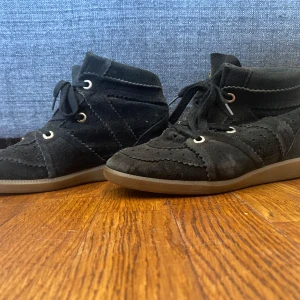 Svarta Isabel Marant skor - Svarta sneakers från Isabel Marant i mjuk mocka med snygga detaljer och snörning. Skorna har en platt sula i gummi och rund tå. Perfekta för dig som gillar en avslappnad men trendig look.