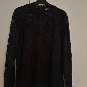 Svart spetsblus - Snygg svart blus med lång ärm och transparent spets upptill och på ärmarna. Hög halsringning och dragkedja bak. Använd 2 ggr och säljes endast pga att den är för stor för mig.