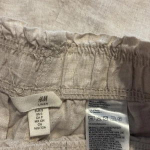 Beiga linnebyxor från H&M, storlek S - Säljer ett par beiga linnebyxor från H&M i storlek S. Byxorna har resår i midjan, raka och vida ben samt fickor i sidorna. Tillverkade i 100% linne!  Använt 1 gång