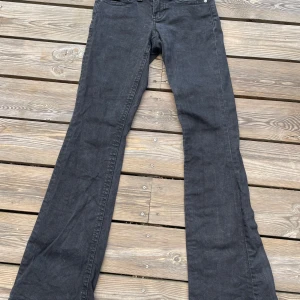 Svarta bootcut jeans från Ginatricot - Snygga svarta jeans från Ginatricot med bootcut passform och klassiska fem fickor. Baktill finns två fickor med lock och silverfärgade knappar. Jeansen har en mörk tvätt och är tillverkade i mjukt bomullsmaterial. 