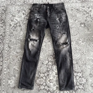 Disquared jeans  - Säljer ett par svarta skinny jeans från Dondup med coola slitningar och trasiga detaljer framtill och baktill. Jeansen har fem fickor, normal midja och en snygg tvättad look. Perfekta för dig som gillar en edgy streetstil.