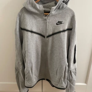 Grå Nike tech hoodie - Tja, säljer min gamla Nike tech hoodie i grå färg. Den här modellen säljs inte längre. Den är i storlek 158/170 och har inte använts på ett bra tag då den inte passar mig längre. Skicket är fint. Vid fler frågor är det bara att skriva. MVH Hugo