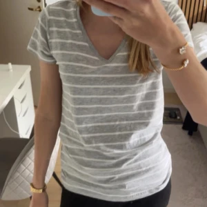 Grå/vit T-shirt - Jag säljer en grå/vit T-shirt från Basic You i storleken S. Kontakta mig om ni vill ha fler bilder!