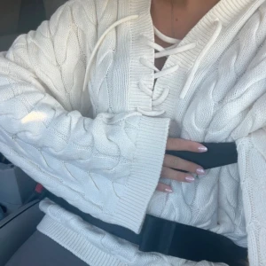 Vit stickad tröja med snörning Gina Tricot - Supermysig vit kabelstickad tröja från Gina Tricot med snygg snörning i halsen och v-ringad krage. 