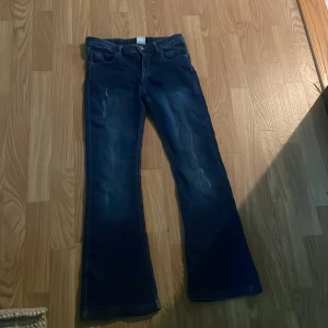 Blå bootcut jeans från Minymo - Snygga blå jeans från Minymo i klassisk bootcut-modell. Jeansen har en mörk tvätt med lätt slitna detaljer och femficksdesign. Perfekta för dig som gillar en retroinspirerad look med lite utsvängda ben. Materialet är klassisk denim.