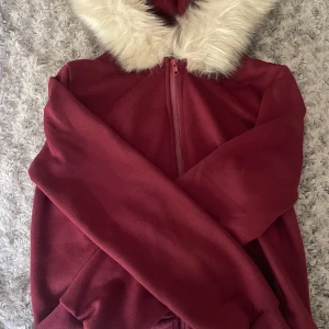 Vinröd kofta med fluff vid huvan  - En superskön kofta med bomull innut i och superskön päls runt om huvan. Är perfekt till vintern som att ha både som vanlig kofta inomhus men även till hösten som en jacka. Är i storlek S, köpt från vinted. 