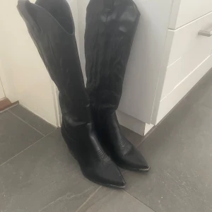 Svarta cowboy boots med klack - Jättefina svarta cowboy boots i skinn med spetsig tå och markerad klack. Klassisk western-design med dekorativa sömmar på skaftet och framtill. Storlek 40 men själv tycker dom är lite stora. Original pris 700kr. Använda en gång.🩷
