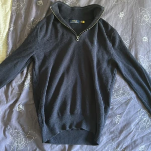 Svart stickad tröja Polo Ralph Lauren - Svart stickad tröja från Polo Ralph Lauren med half zip-dragkedja och hög krage. Klassisk och stilren design med långärmade ärmar och diskret logga på bröstet. Perfekt för dig som gillar enkel och snygg stil. Passar dig som är 170-177~, säljs pga växt ut! Pris kan diskuteras vid snabb affär, nypris kring 1200