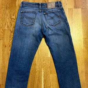 Jacob Cohën Jeans - Säljer ett par jeans från Jacob Cohën. Storlek 32.  Slitningar på båda benen för en trendig look.  Handgjorda i Italien, perfekta för dig som letar efter hög kvalitet och trendiga jeans.