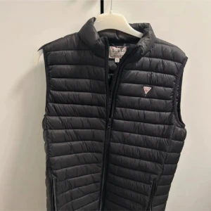 Svart dunväst från Guess - Snygg svart dunväst från Guess. Jättesnygg och i bra skick. 