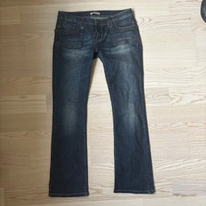 Mörkblå lågmidjade bootcut jeans  - Snygga mörkblå lågmidjade jeans från Dr. Denim med bootcut passform och klassiska fickor både fram och bak. Jeansen har låg midja och är tillverkade i ett mjukt bomullsmaterial med lite stretch. Perfekta för dig som gillar en avslappnad men ändå stilren look.